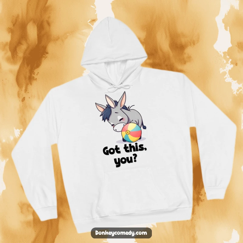 Funny donkey hoodie depicting a charming donkey playfully nudging a colorful ball with its nose, radiating warmth and fun.