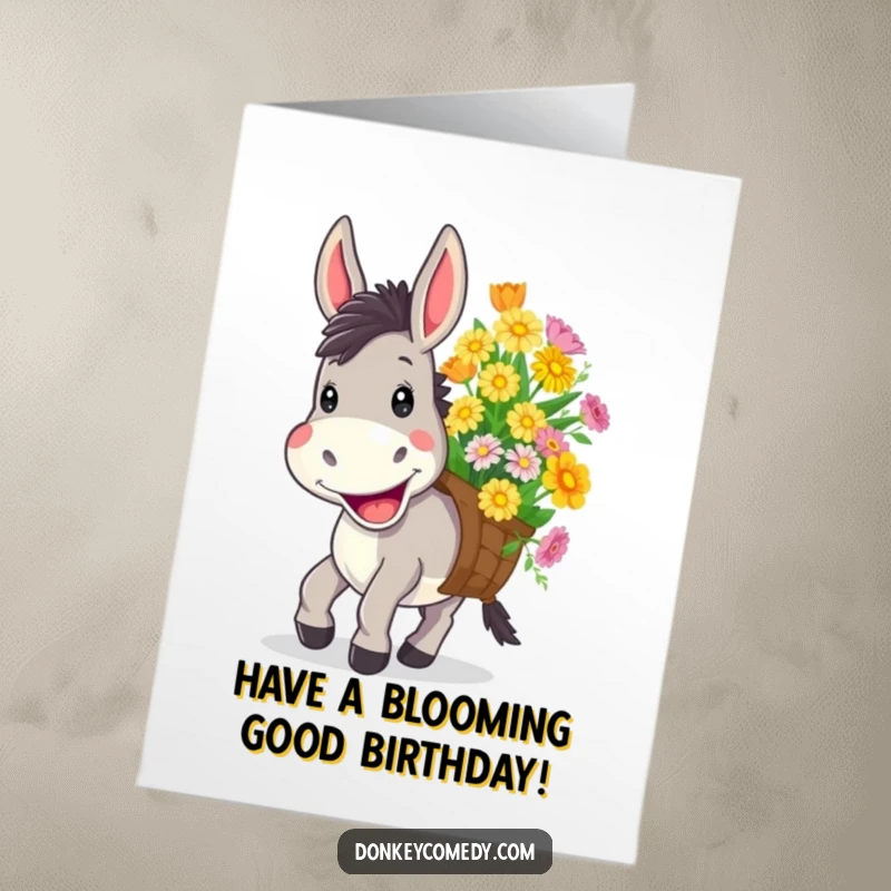 Funny free printable birthday card featuring a donkey with a wide, cheerful grin carrying a load of colorful flowers.
